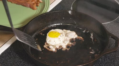 Poêle en fonte sur la cuisinière, faire frire l'œuf et le retirer de la poêle