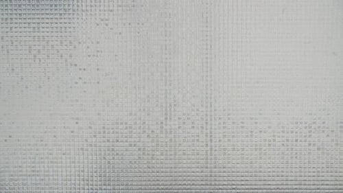 Un panneau de diffusion en grille translucide sur une fenêtre.