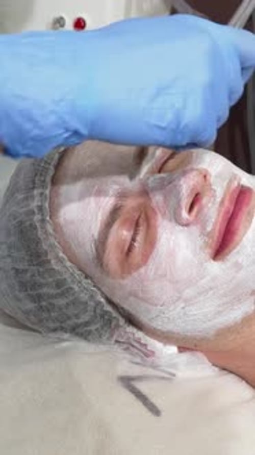 Relaxed Man Enjoying Rejuvenating Facial Mask at Beauty Salon