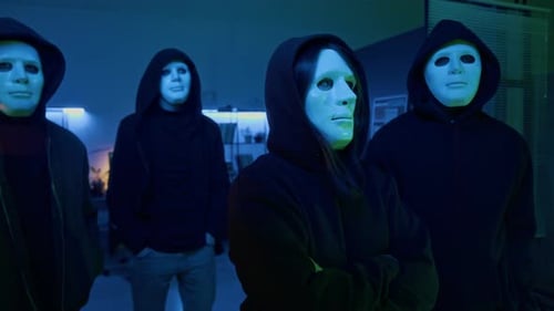 Groupe de cybervoleurs masqués professionnels dans le bureau obscur d'une entreprise informatique