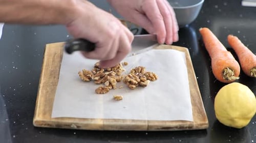 Close-up chopping walnuts on a cutting board.