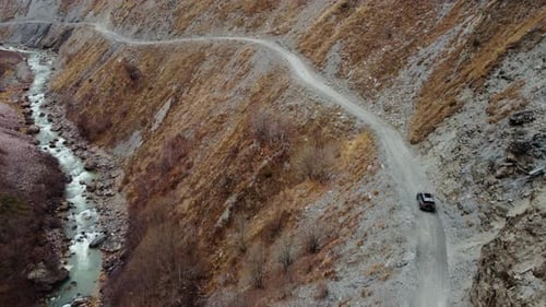 Car Is Riding Winding Road Through a Rugged Mountain Valley