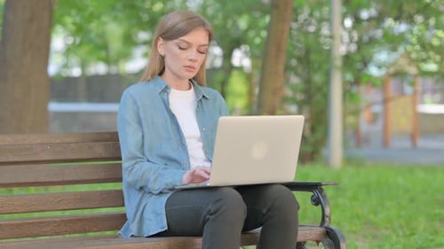Young Woman Works on Laptop in Sunny Park