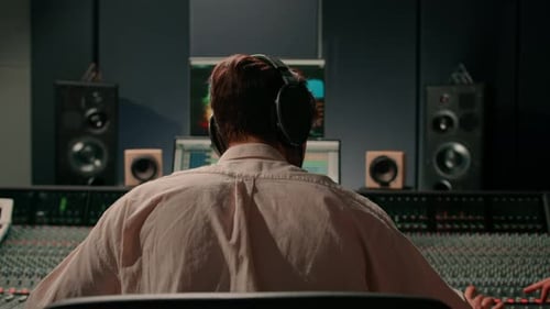 Energetic audio engineer producer working in recording studio mixing tracks on console and hit maker