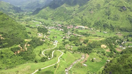 Aerial view of lush valley and village surrounded by mountains, Vietnam.