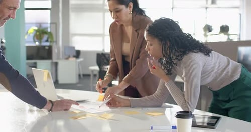 Divers collègues organisant un organigramme à la table après qu'un homme senior ait pointé des notes autocollantes pour la planification