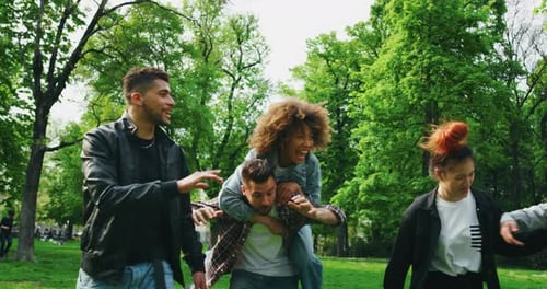 Slow motion of group of young friends of different ethnicities are having fun together in a green