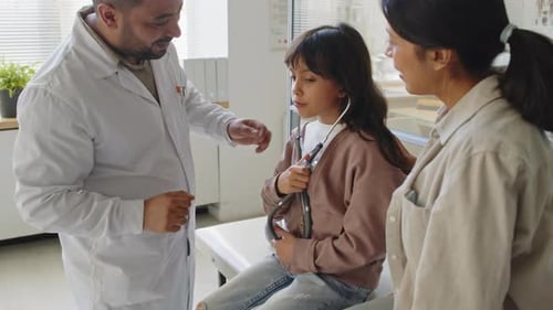 Little Girl Using Stethoscope at Doctors Office