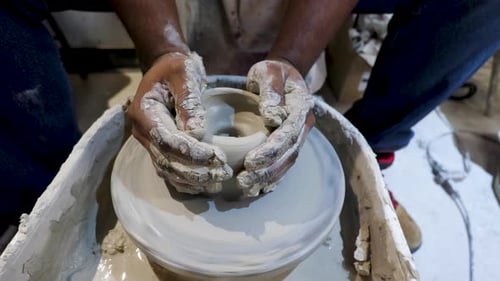 overhead close view of an African American hands spinning clay very sporadically