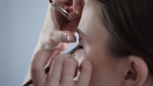 Künstler schminkt sich drinnen wunderschön auf das Gesicht einer Frau, Nahaufnahme