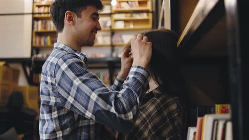Romantic Couple Embracing by Bookshelf in Library