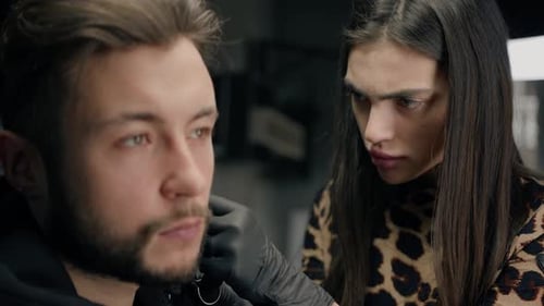 Tattoo piercing studio - a woman makes an ear piercing to a man to a guy