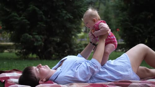 Mom Plays with Infant in Park Lifting Her in Air