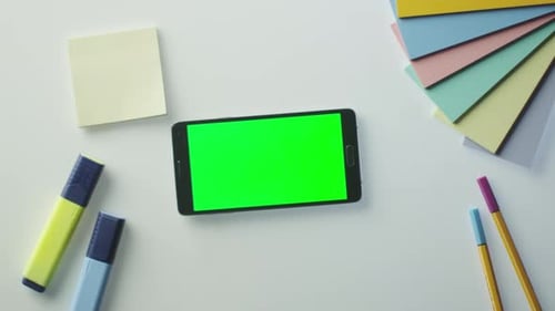 O designer está usando um telefone Android com tela verde no modo paisagem. Vista superior.