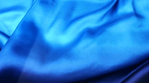 Natürlicher blauer Seidenstoff, der im Wind flattert und abstrakte fließende Wellen erzeugt.