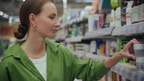 Woman Choosing Cosmetics Using Smartphone in Supermarket