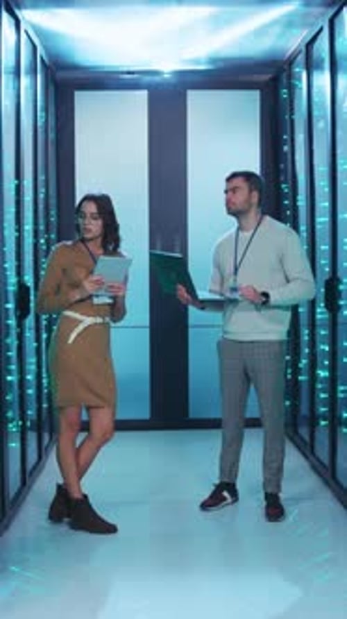 Two Highly Skilled Professionals Working in a Modern Data Center Environment Setting