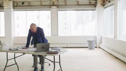 Mature architect confidently planning office remodel on laptop in modern office