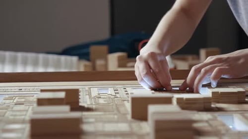 Hands of Professional Man Constructing Architecture Model of Urban City Building