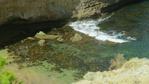 Slow Motion Shot of Waves Crashing of Rocks at the Bottom of a Cliff