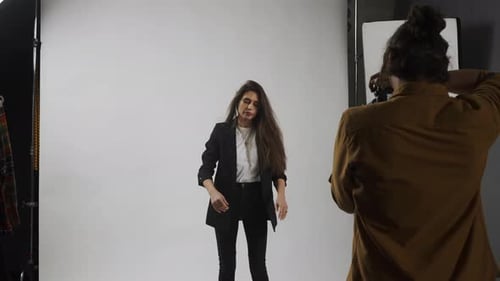 Modelo y equipo de producción en el estudio: mujer en traje posando para un fotógrafo posando, actuando, maquillándose