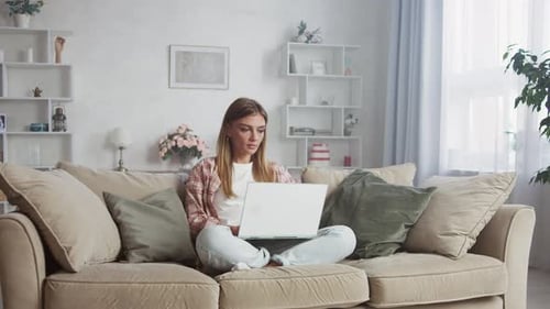 Woman Using Laptop Computer on Sofa at Home