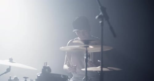Un jeune batteur qui fait tourner des baguettes sur scène sous les projecteurs