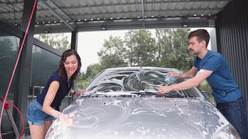 Couple Washing Silver Car at Outdoor Carwash