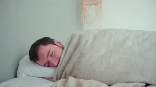 Homme endormi, blanc caucasien avec barbe, jeune homme couché dans son lit en train de rêver, pi mal à l'aise