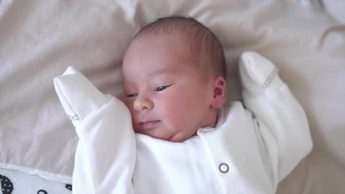 Funny infant. Adorable newborn baby sleeping and yawning on bed. Lovely toddler at home. Close-up