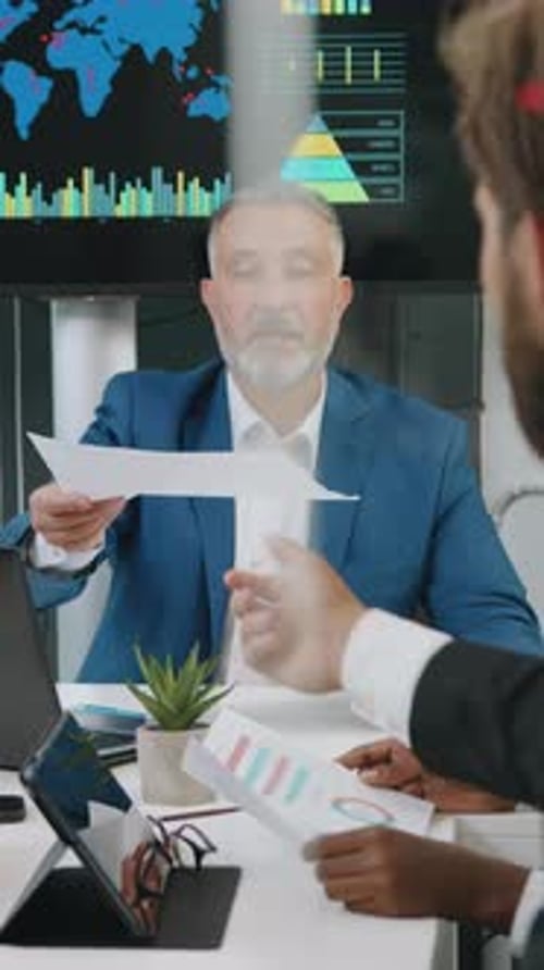Businessmen Reviewing Charts and Graphs in a Meeting