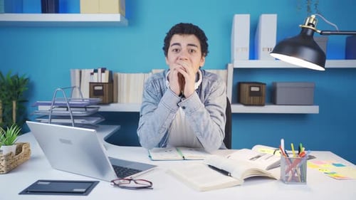 An unhappy male student looking at the camera and waiting for news is depressed.