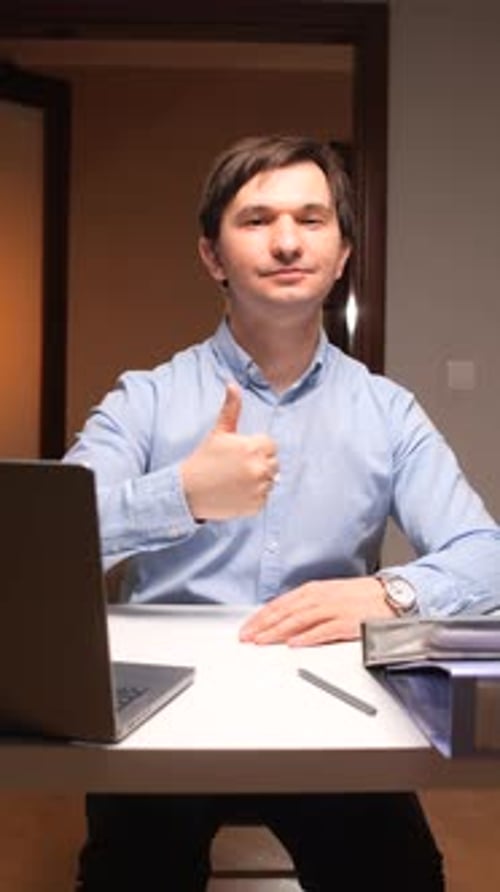 Vertical Video Office Worker Gesturing Thumbs Up While Working on Laptop