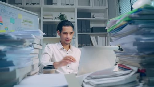 Exhausted Asian young businessman worker working on table in office workplace.