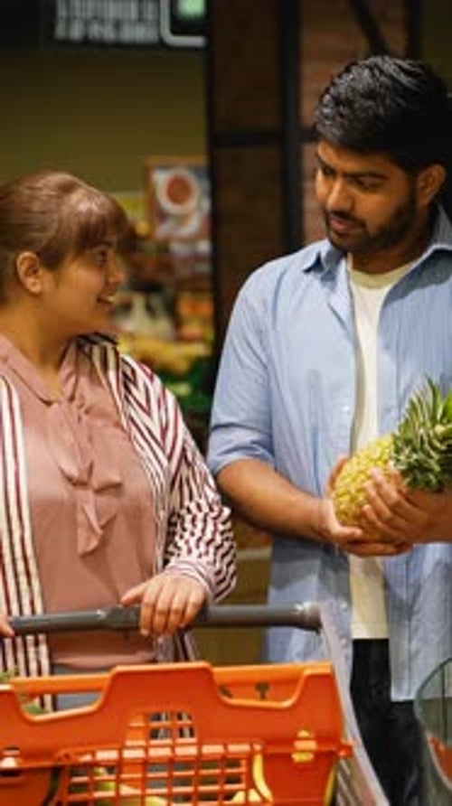 Young Couple Shopping for Groceries and Choosing a Pineapple