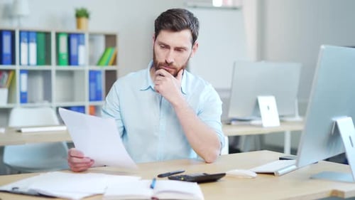 Man looks at paper at his desk in office