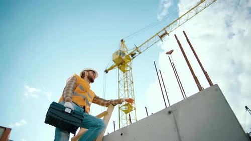 Construction Worker Climbing Ladder at Construction Site