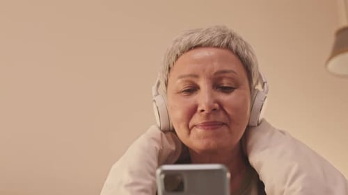 Senior Asian Woman Using Smartphone in Bed at Night