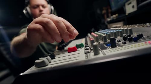 A close-up of a mixing console device used by a man working as professional sound engineer