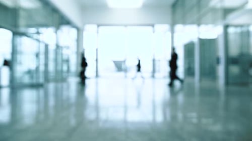 Blurred scene people walk inside a bright, modern building