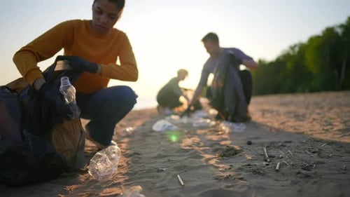Freiwillige Leute sammeln Müll und sortieren Müll in Säcken an der Meeresküste bei Sonnenuntergang
