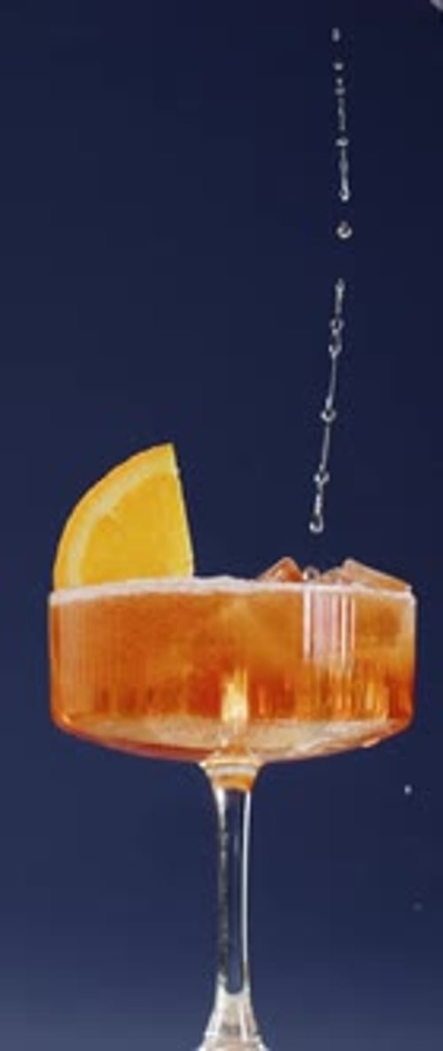 Vertical Video of Bubbles in Orange Cocktail with Ice and Fruit