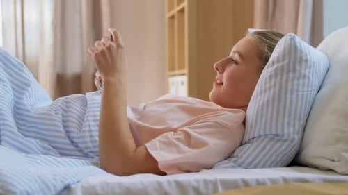 Woman Lies in Bed Using Mobile Phone