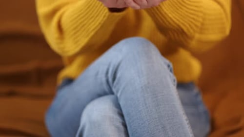 A Woman Sitting on a Couch Presented a Small Gift in the Palms of Her Hands - Close Up