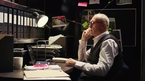 Man Working in Dark Office on Telephone