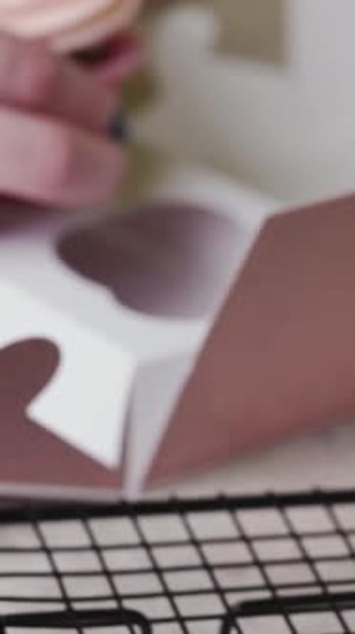 A pastry chef young woman puts cupcakes in a gift box. Vertical video.