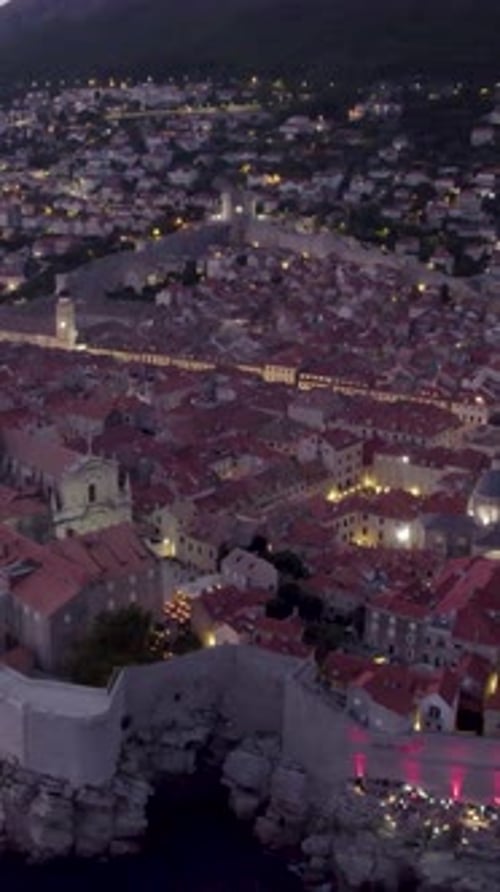Aerial view of Dubrovnik old town illuminating at dusk, Croatia. Vertical Video
