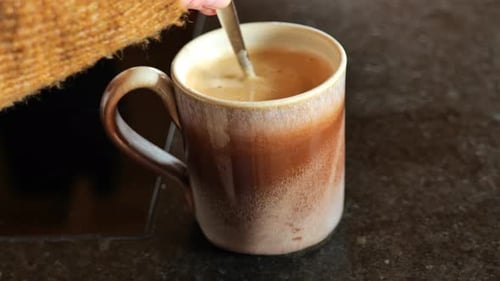 Coffee Cup Being Stirred with a Spoon