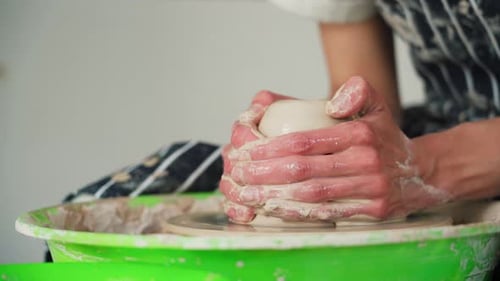 Une potière travaille sur un tour de potier et fabrique un pot en céramique en argile dans un atelier de poterie.