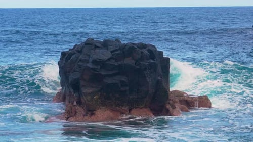 Waves crashing against rocky formations in a serene coastal landscape